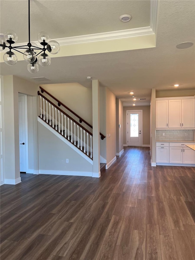 unfurnished living room with stairway, baseboards, dark wood finished floors, crown molding, and a raised ceiling