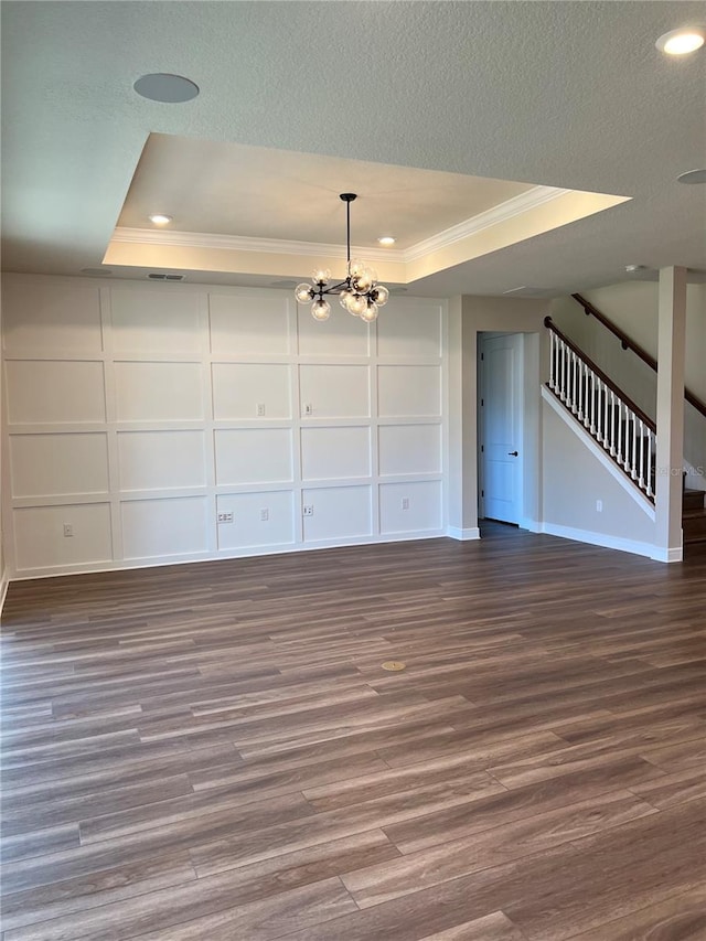 interior space with a notable chandelier, a tray ceiling, a textured ceiling, wood finished floors, and stairs