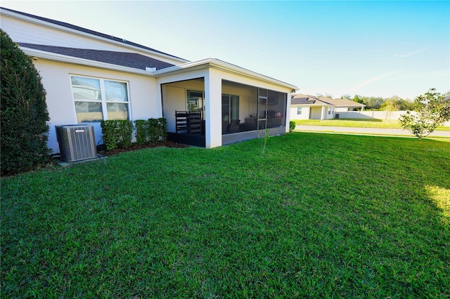 rear view of house with a yard, cooling unit, a sunroom, and stucco siding