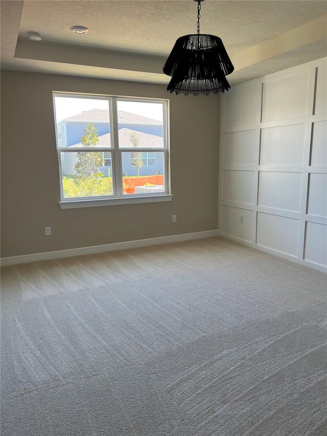 unfurnished room with a decorative wall, light colored carpet, baseboards, and a textured ceiling