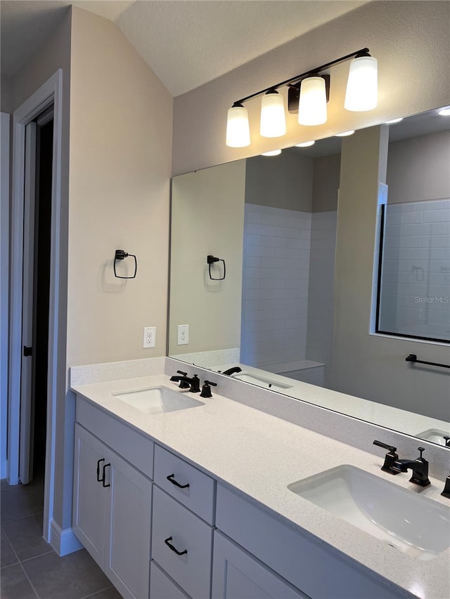 full bath with a sink, lofted ceiling, double vanity, and tile patterned flooring