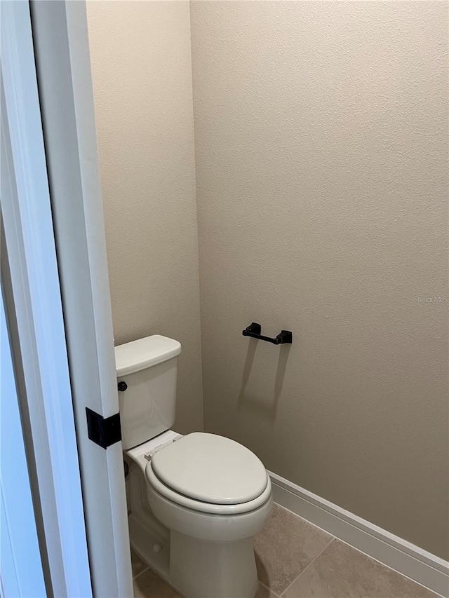 bathroom featuring tile patterned floors, baseboards, and toilet