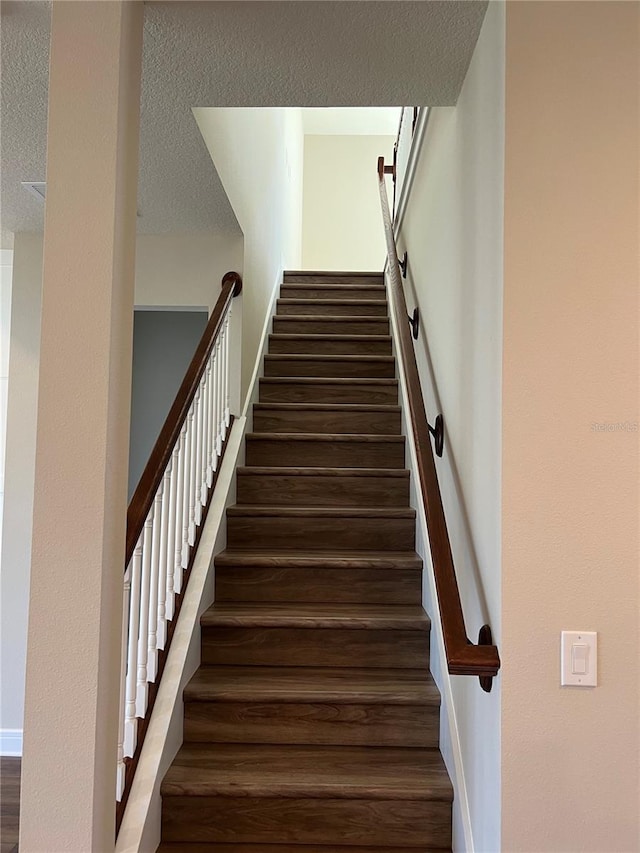 staircase featuring a textured ceiling