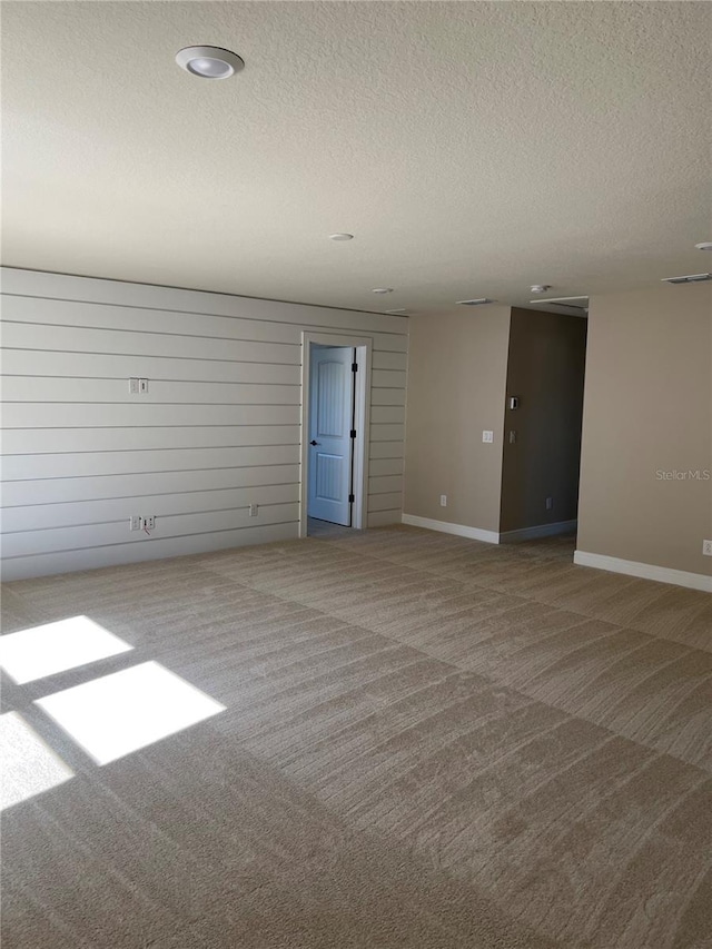 carpeted spare room with visible vents, a textured ceiling, and baseboards