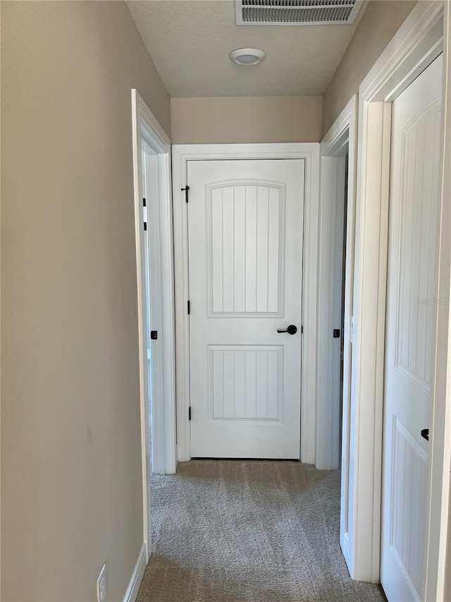 hallway featuring carpet flooring and visible vents