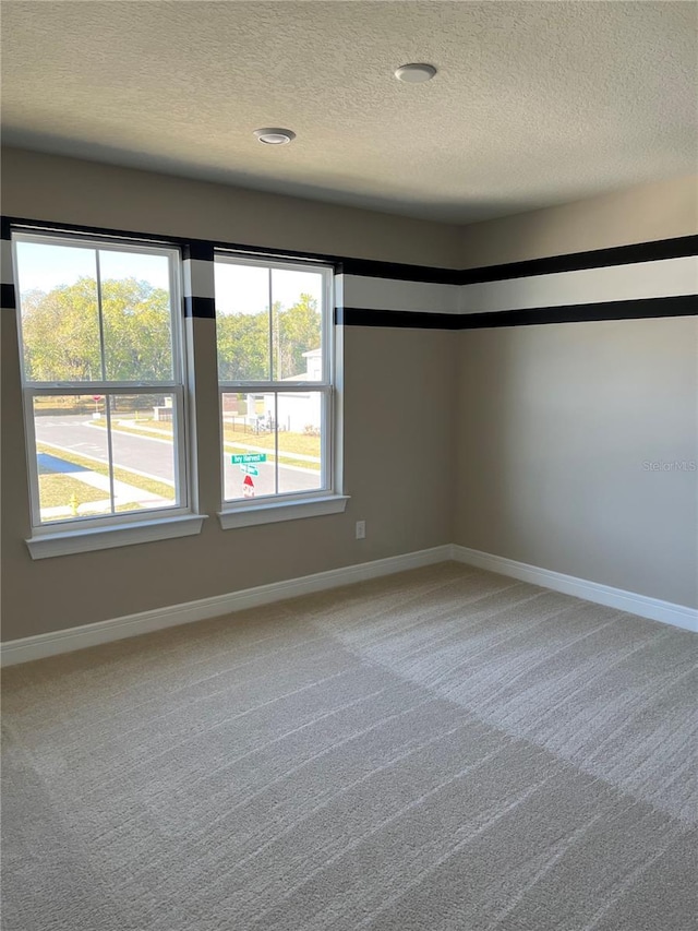 spare room with baseboards, a textured ceiling, and carpet flooring