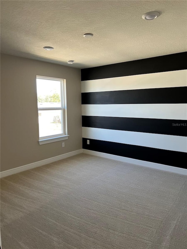 spare room featuring baseboards, carpet floors, and a textured ceiling