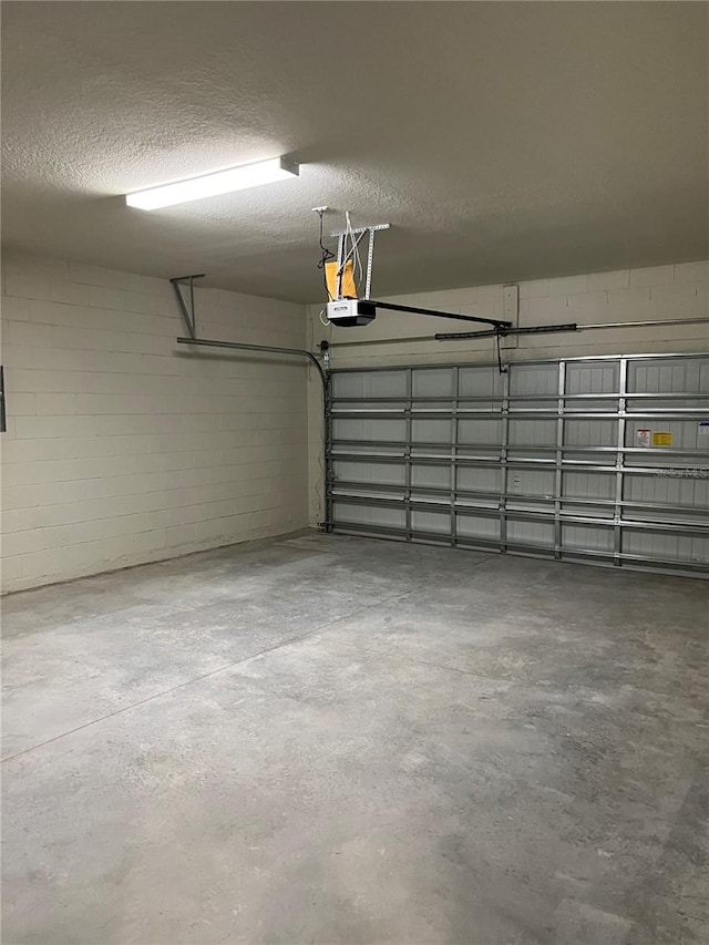 garage featuring a garage door opener and concrete block wall