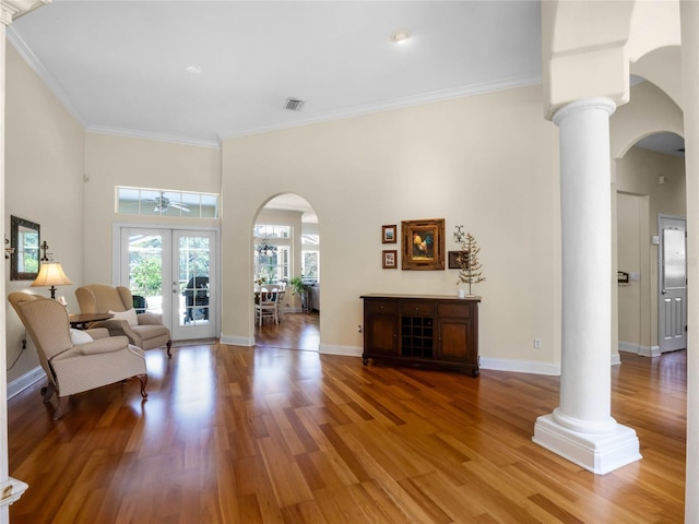 living room featuring french doors, arched walkways, wood finished floors, and ornate columns