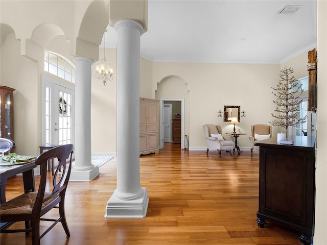 foyer entrance with visible vents, ornamental molding, light wood-style floors, and decorative columns