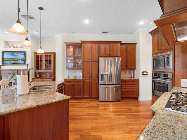 kitchen with brown cabinetry, visible vents, stainless steel appliances, and a sink