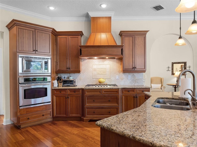 kitchen with visible vents, dark wood-style flooring, a sink, stainless steel appliances, and custom range hood