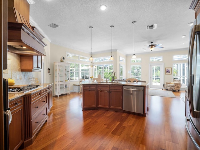 kitchen with visible vents, a sink, open floor plan, appliances with stainless steel finishes, and ceiling fan