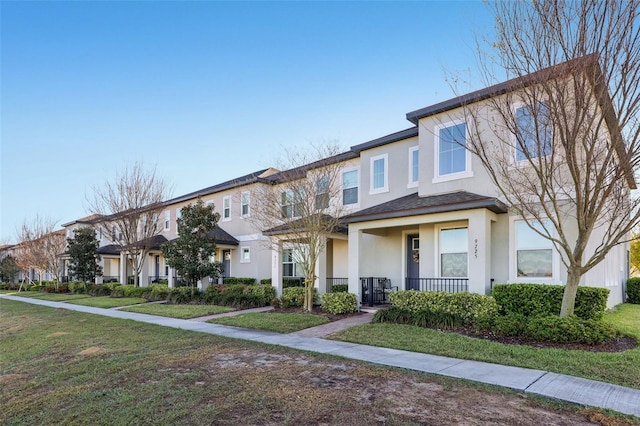 view of property featuring a residential view, stucco siding, a porch, and a front lawn