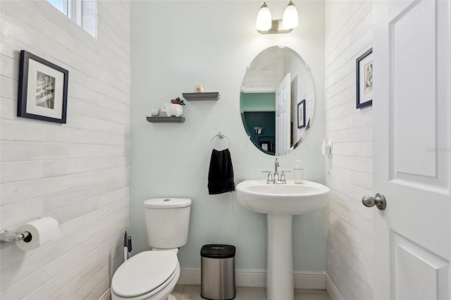 half bath with a sink, baseboards, and toilet