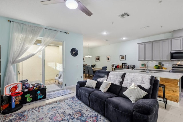 living area with plenty of natural light, ceiling fan with notable chandelier, visible vents, and light tile patterned floors