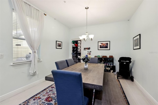 dining space featuring light tile patterned flooring, a notable chandelier, and baseboards