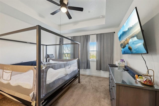 bedroom with light carpet, a raised ceiling, and baseboards