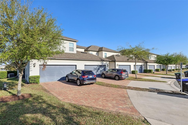 townhome / multi-family property with decorative driveway, a garage, and stucco siding