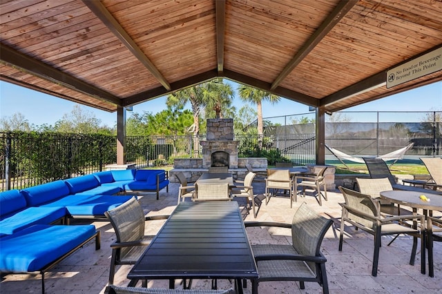 view of patio / terrace with an outdoor living space with a fireplace, outdoor dining space, and fence