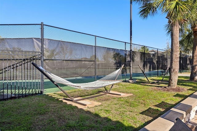 exterior space with a tennis court, a yard, and fence