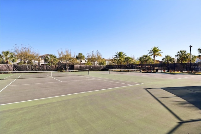 view of tennis court with community basketball court and fence