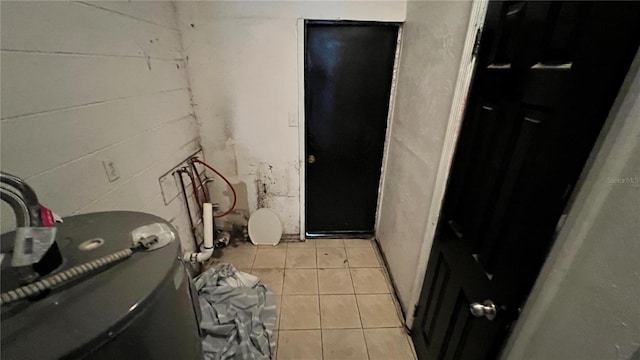 interior space with concrete block wall and light tile patterned flooring