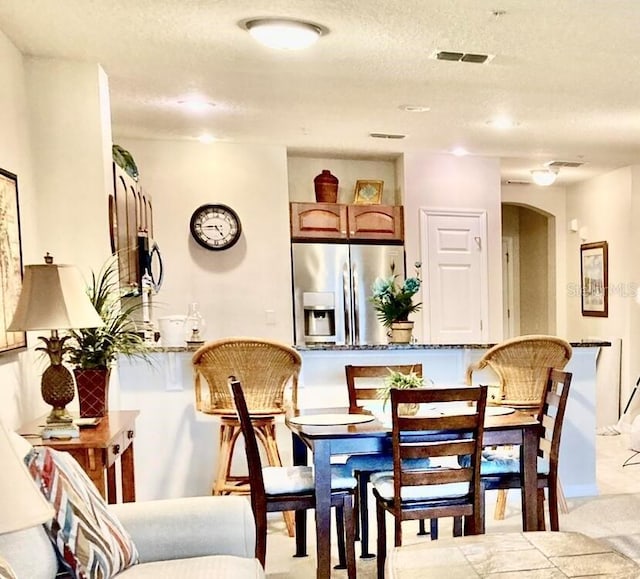 dining area with visible vents, arched walkways, and a textured ceiling