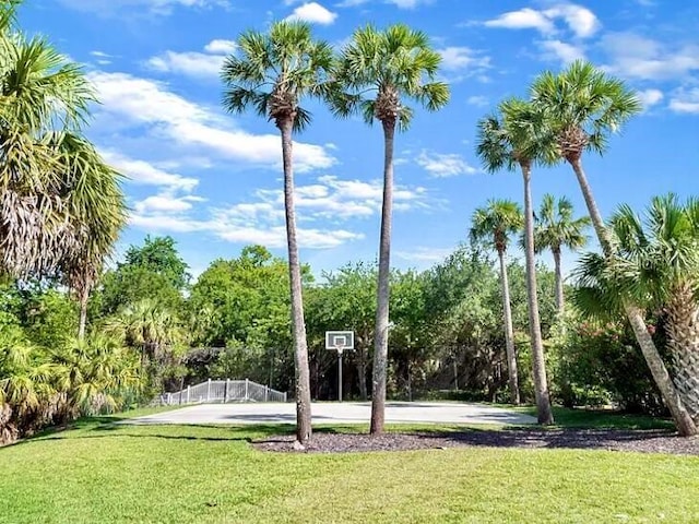 exterior space featuring a yard, community basketball court, and fence