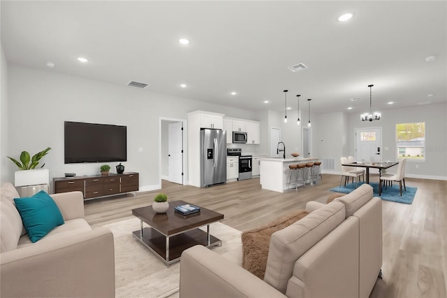living room with visible vents, an inviting chandelier, and recessed lighting