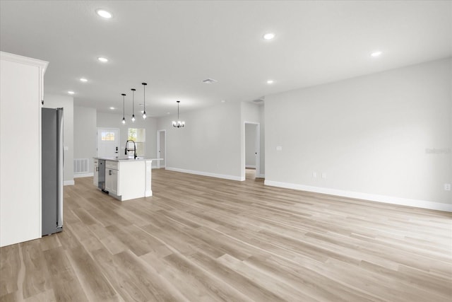 unfurnished living room with recessed lighting, baseboards, a sink, light wood finished floors, and visible vents