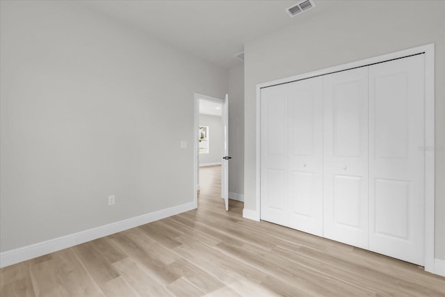 unfurnished bedroom with baseboards, visible vents, a closet, and light wood finished floors