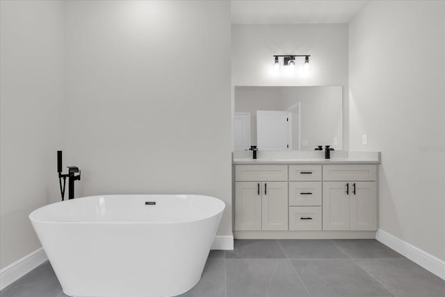 bathroom featuring a sink, double vanity, a freestanding tub, and baseboards