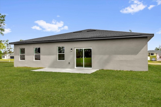 rear view of house featuring a lawn, stucco siding, and a patio