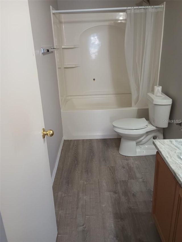 full bathroom with baseboards, toilet, shower / tub combo with curtain, wood finished floors, and vanity