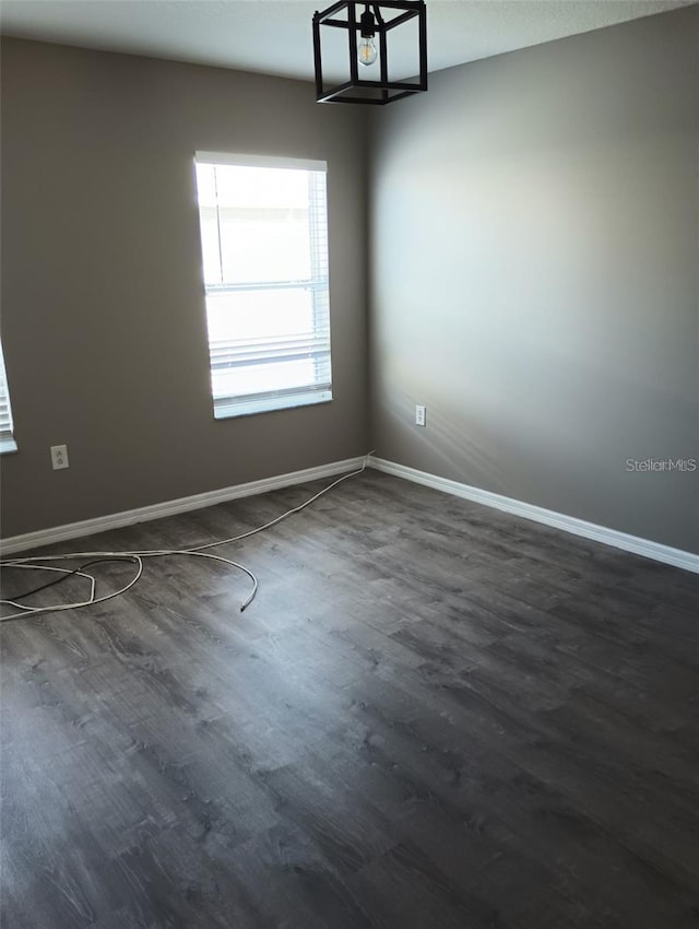 unfurnished room with dark wood finished floors and baseboards