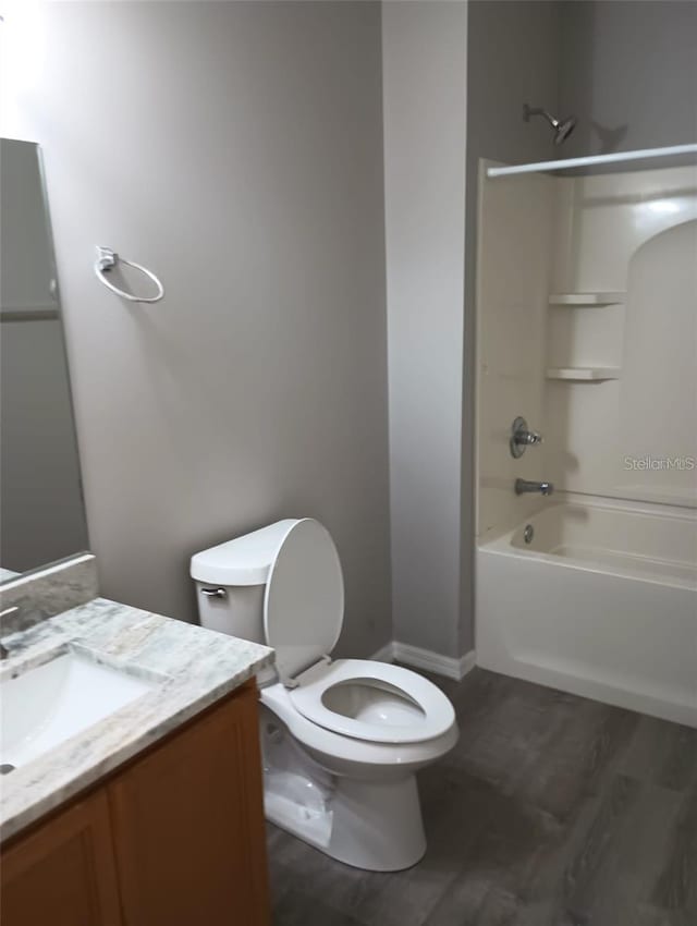 full bath featuring toilet, wood finished floors, vanity, and shower / tub combination