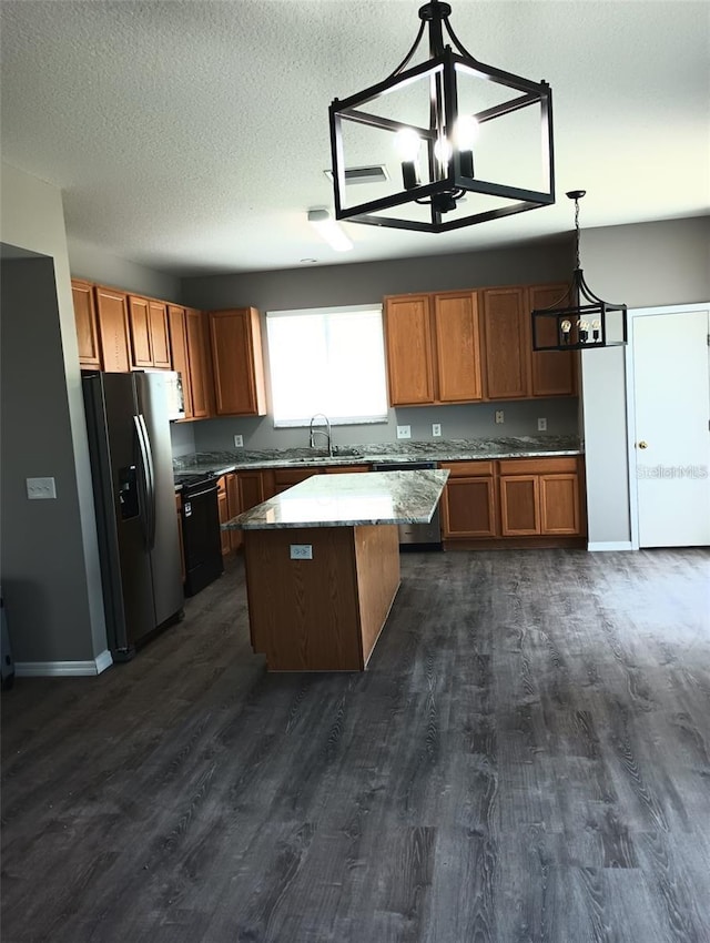 kitchen featuring brown cabinetry, stainless steel fridge with ice dispenser, a sink, dark wood-type flooring, and a center island