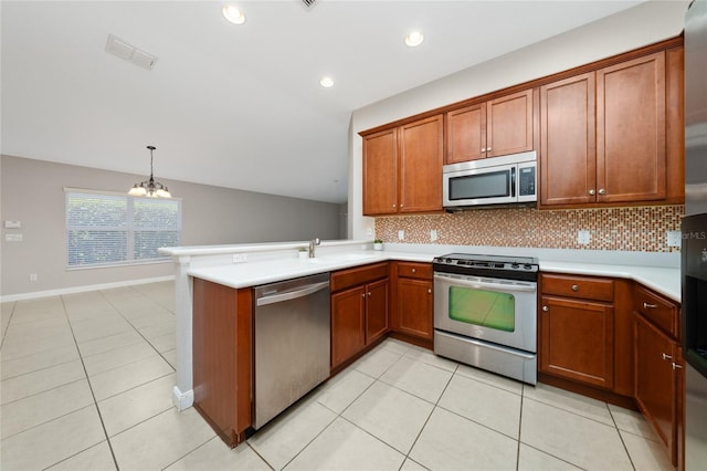 kitchen with brown cabinetry, a peninsula, light countertops, appliances with stainless steel finishes, and tasteful backsplash