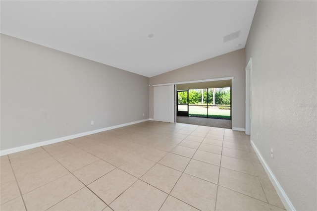 spare room featuring light tile patterned floors, visible vents, baseboards, and vaulted ceiling