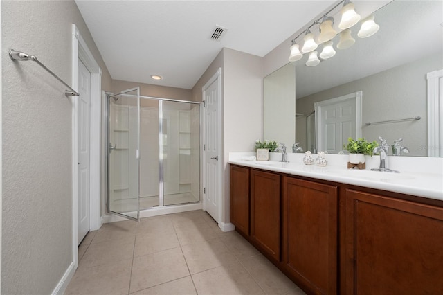 bathroom with double vanity, visible vents, a stall shower, and a sink