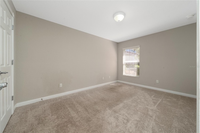 unfurnished room featuring light carpet and baseboards