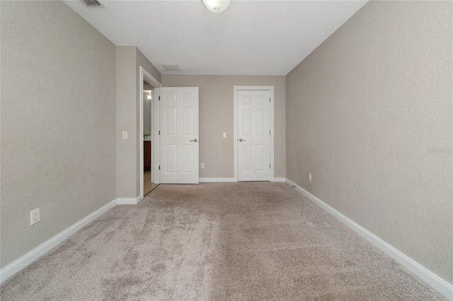 carpeted spare room with visible vents and baseboards