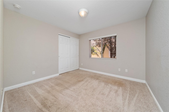 unfurnished bedroom featuring a closet, baseboards, and carpet