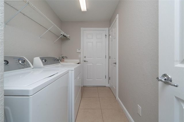 washroom featuring a sink, laundry area, light tile patterned floors, and washer and clothes dryer