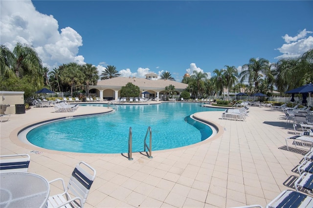 community pool with a patio area and fence