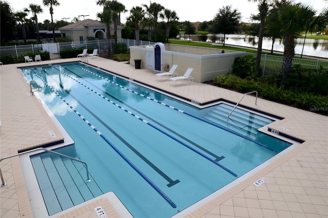 community pool featuring a patio area, a water view, and fence