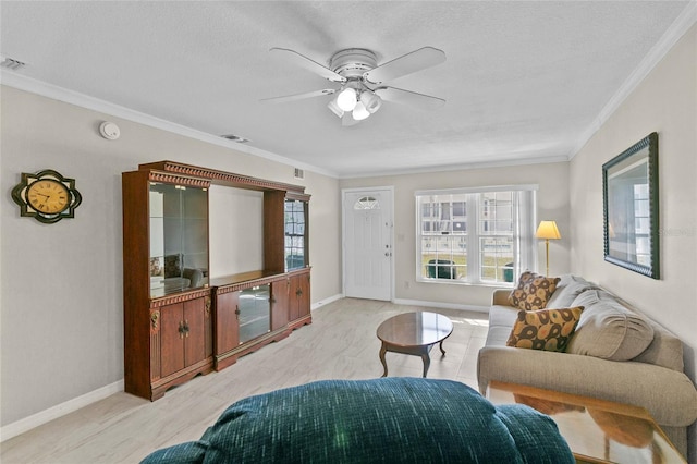 living area with visible vents, a ceiling fan, a textured ceiling, crown molding, and baseboards