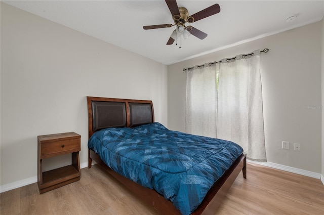 bedroom with light wood-style flooring, a ceiling fan, and baseboards