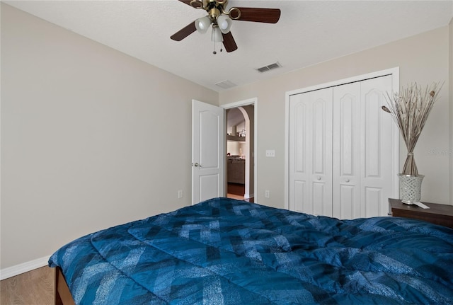 bedroom featuring visible vents, baseboards, wood finished floors, a closet, and a ceiling fan